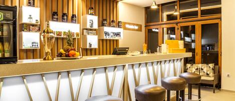 A bar area with wooden paneling, a counter with stools, and shelves with various items.
