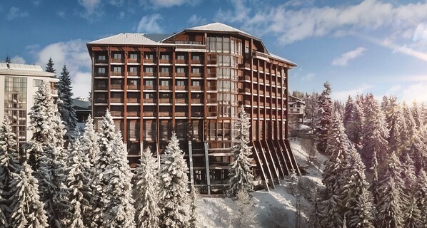 A multi-story hotel with a modern architectural design, surrounded by snow-covered trees. - Hotel Orlovetz (Chepelare)