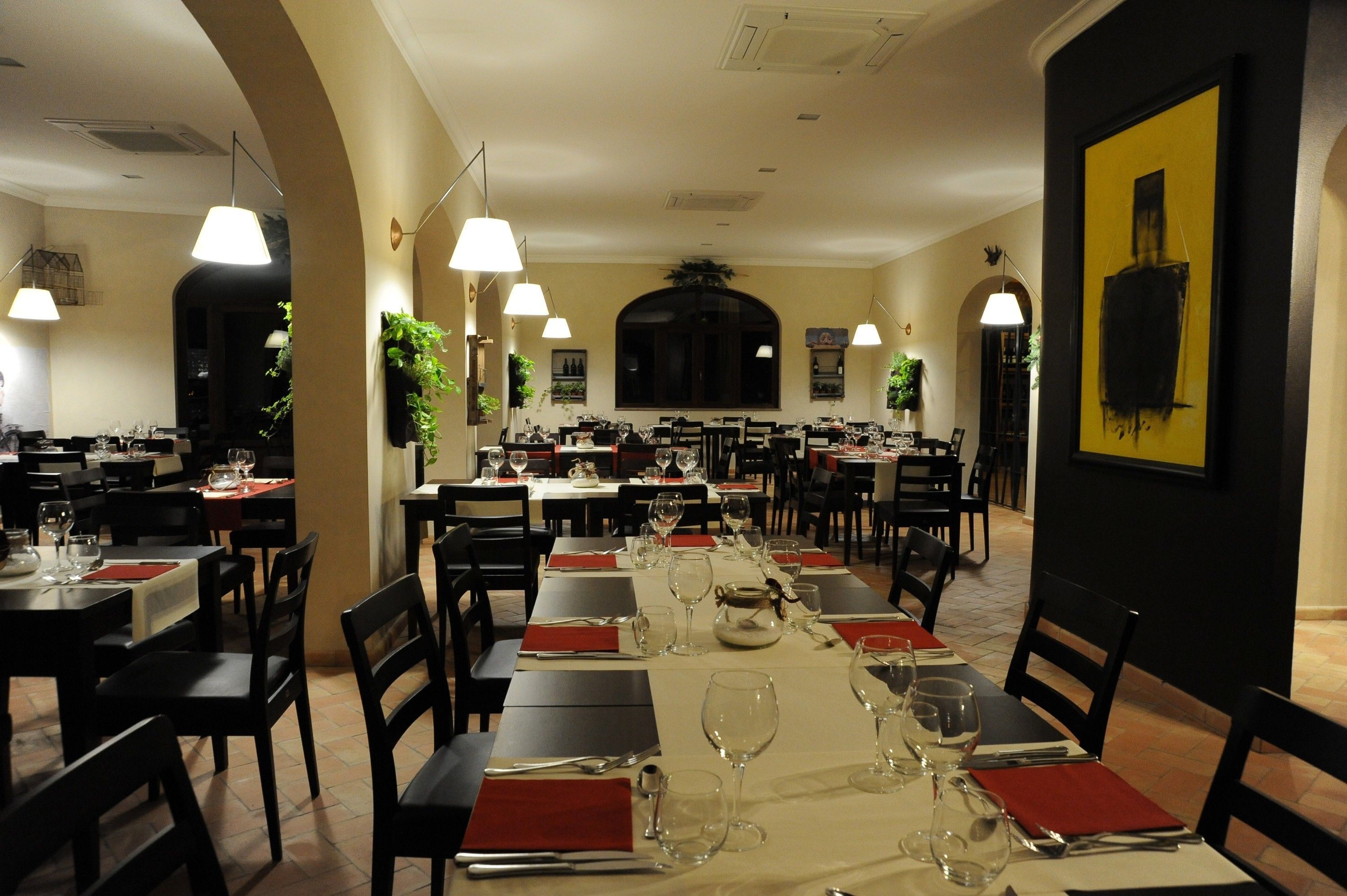 Ein Restaurant mit mehreren Tischen, eingerichtet für Speisen, das einen zentralen Essbereich mit einem langen Tisch und kleineren Tischen rundherum bietet.