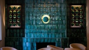 Een kamer met een glazen wand met patroon, een ronde lamp en drie stoelen.