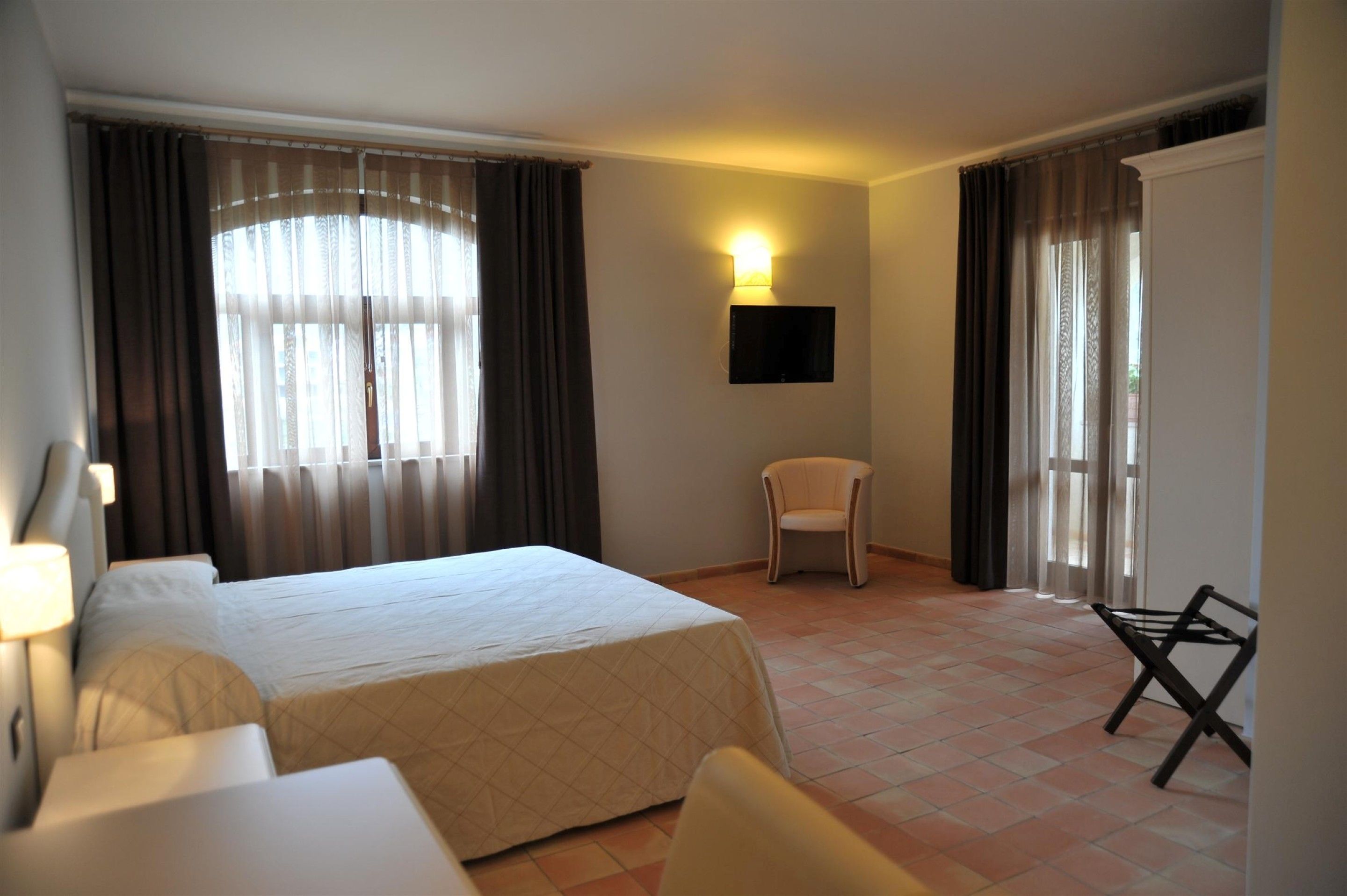Une chambre d’hôtel équipée d’un lit, d’une chaise, d’un bureau et d’un téléviseur fixé au mur.