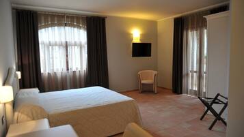 Une chambre d’hôtel équipée d’un lit, d’une chaise, d’un bureau et d’un téléviseur fixé au mur.