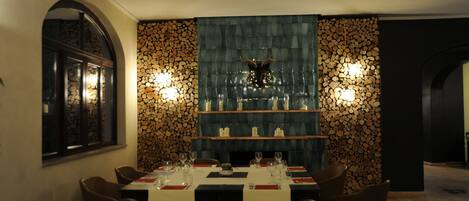 Un comedor con una mesa preparada para cuatro personas, una chimenea y una pared decorativa con un venado como adorno.