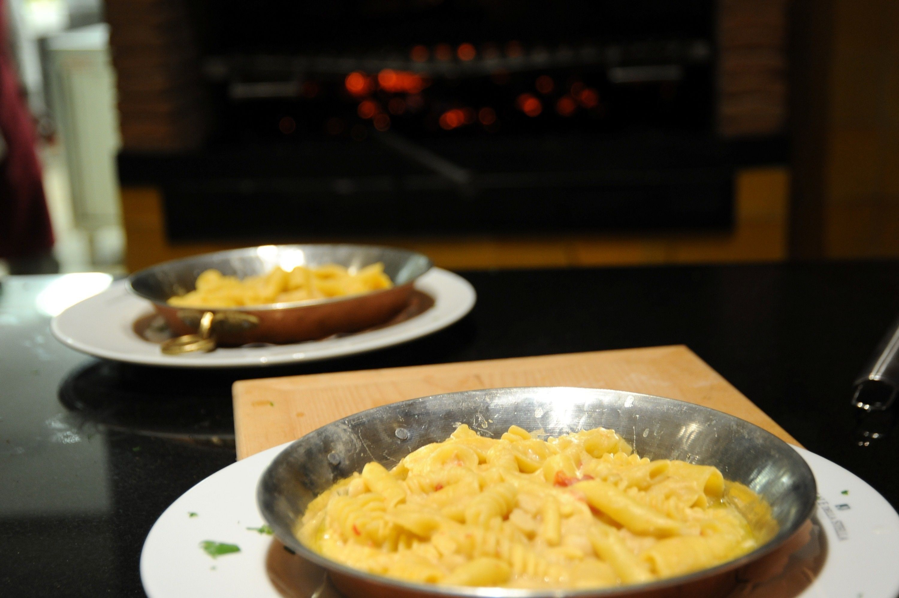 A dining table with two metal bowls containing pasta dishes.