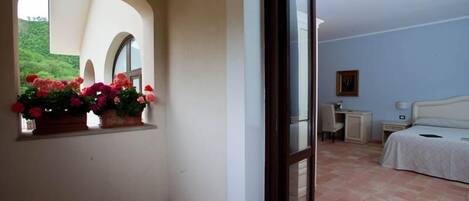 Une chambre à coucher avec un lit, un bureau, une chaise, une table de chevet et une fenêtre décorée de fleurs.