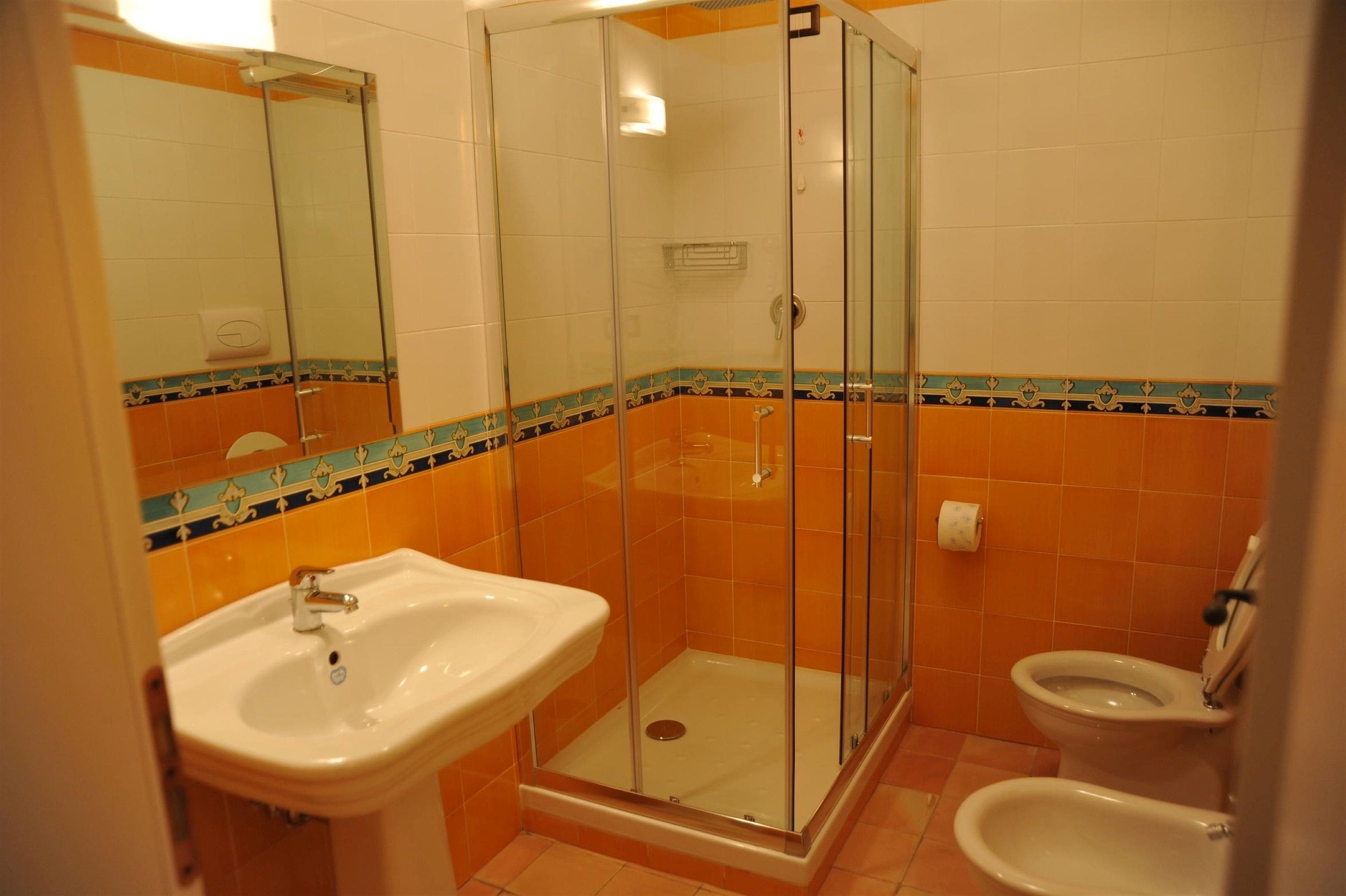 Een badkamer met een douchecabine van glas, een wastafel en een toilet.