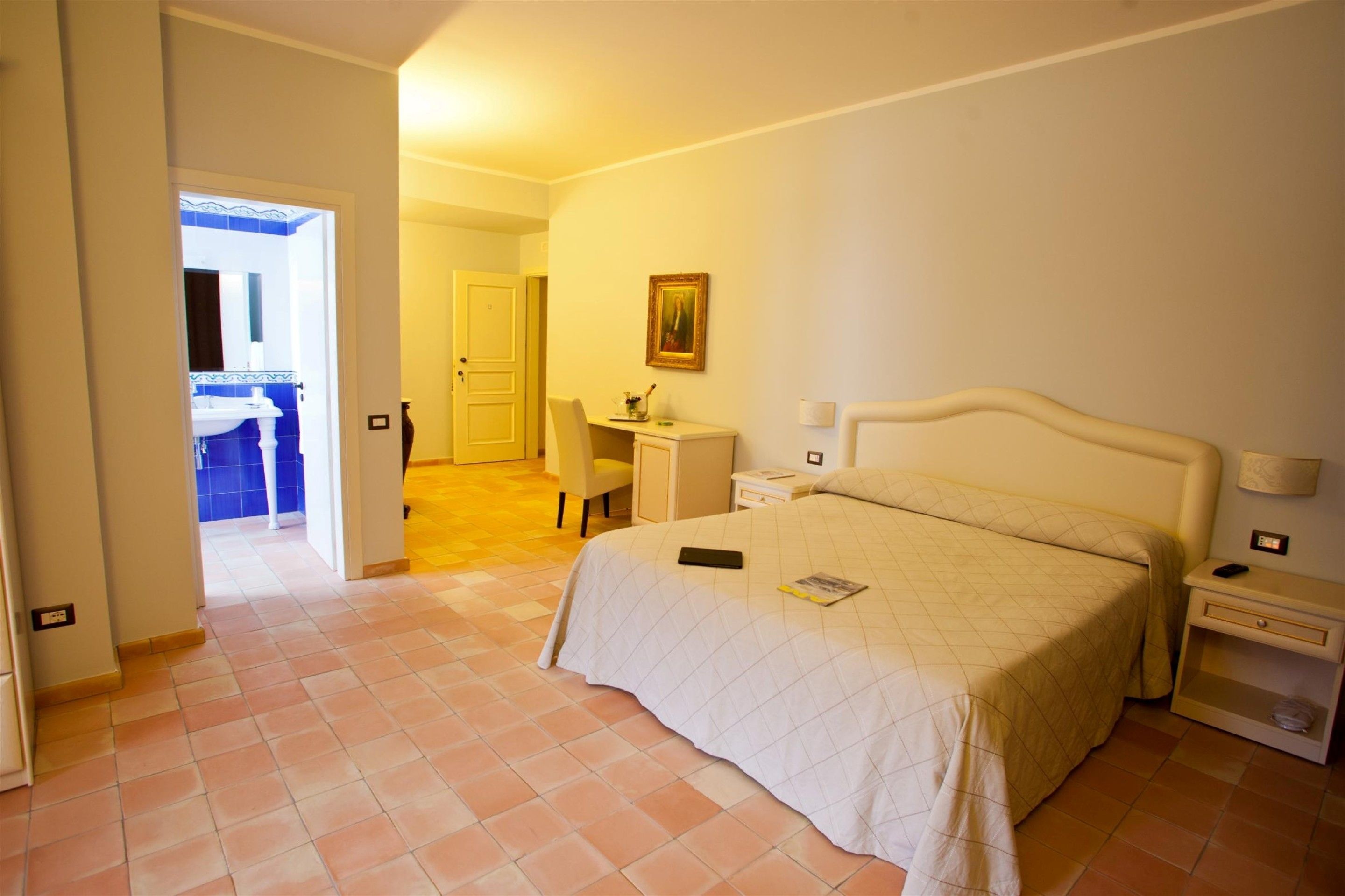 Un dormitorio con cama, mesitas de noche, escritorio y silla.