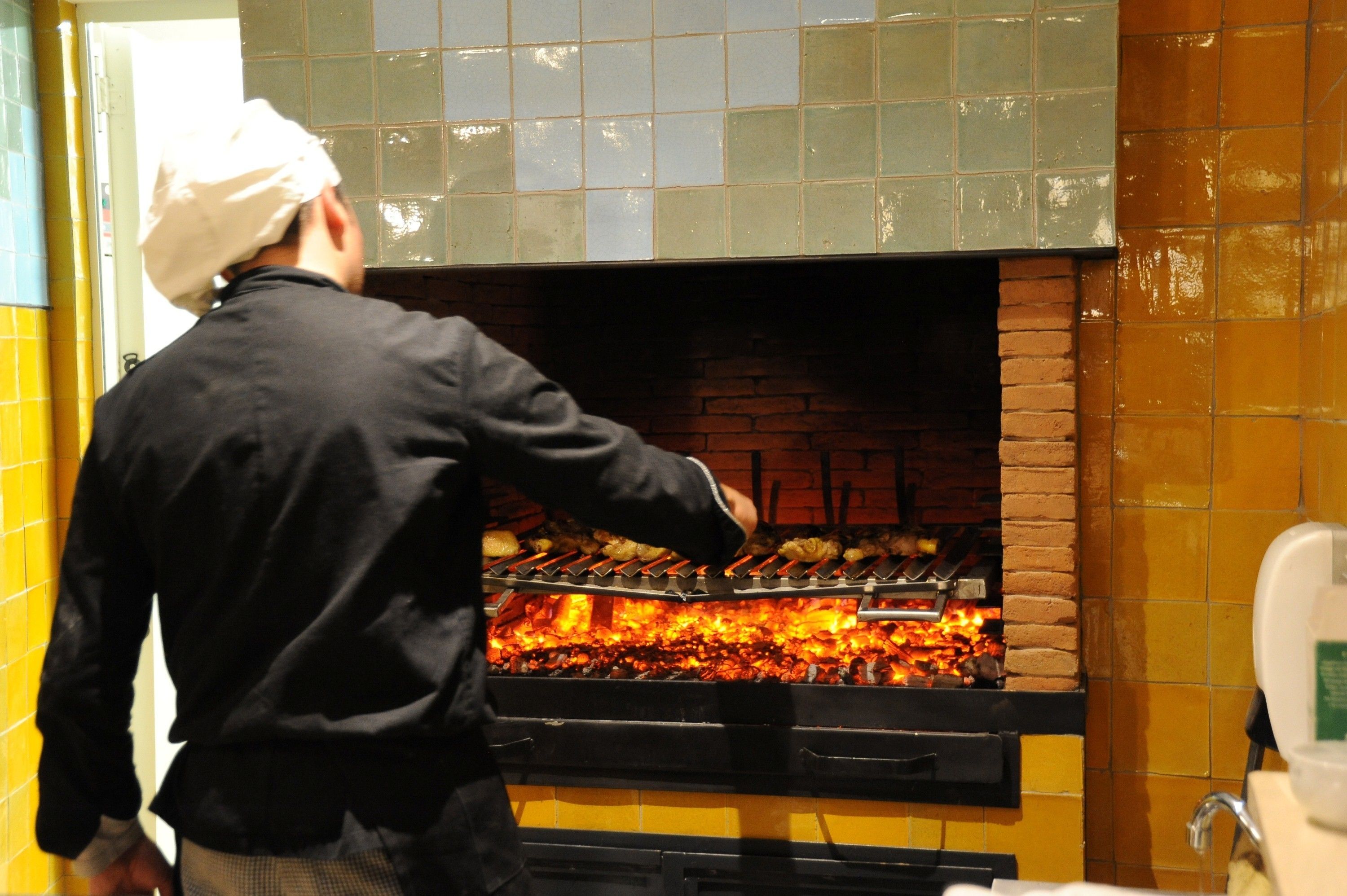 Un chef qui dispose des aliments dans un four en briques.