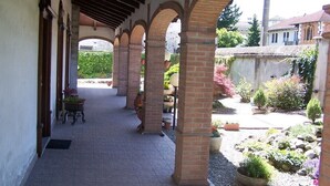 A covered walkway with brick columns, potted plants, and a gravel path. - Hotel Ristorante La Torretta (Bianze)