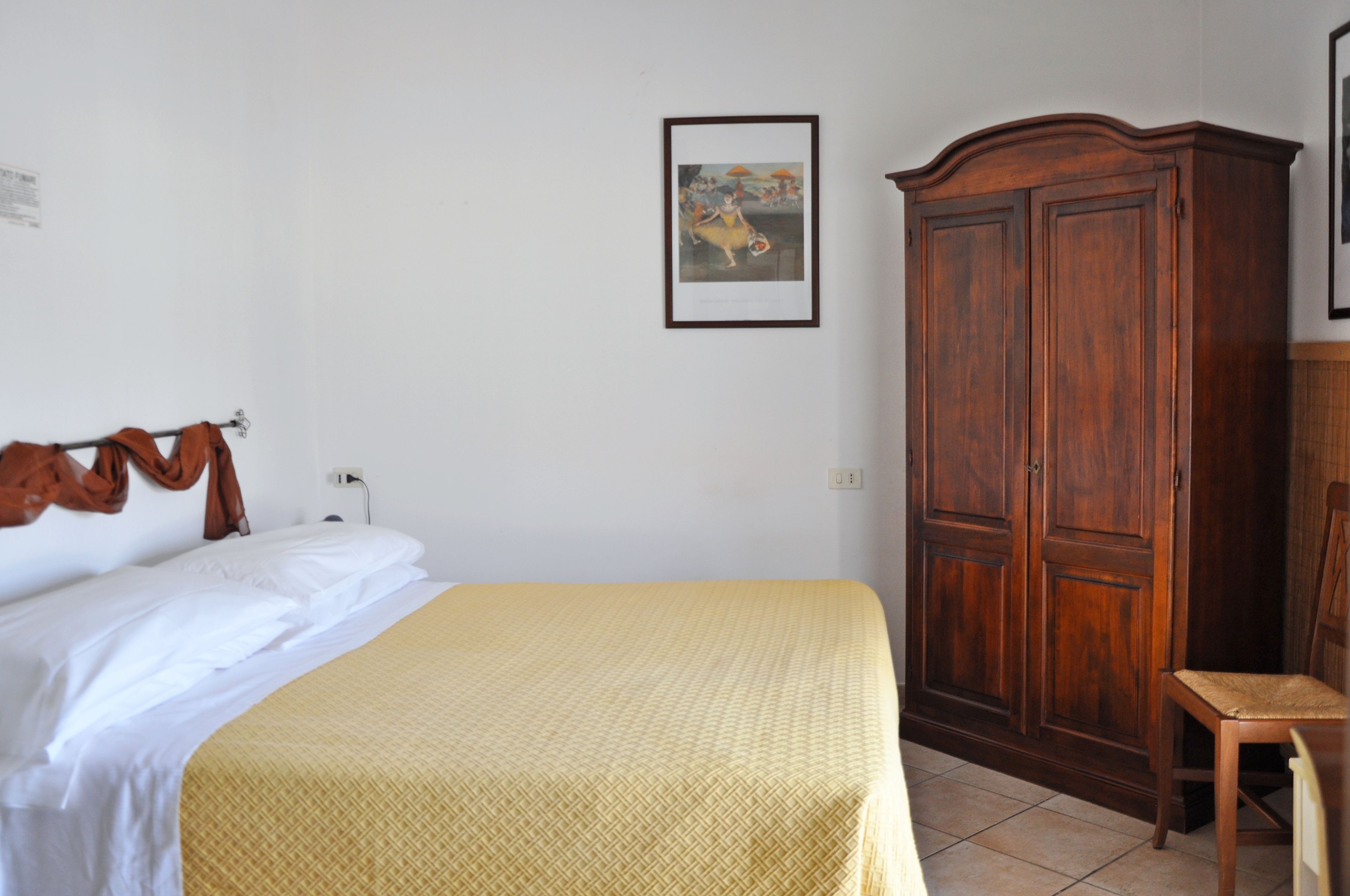 Ein Zimmer mit einem Bett, einem Holzschrank und einem Stuhl.