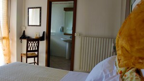 A hotel room with a bed, a desk with a telephone, a chair, a mirror, and a bathroom visible through an open door. - Hotel Ristorante La Torretta (Bianze)