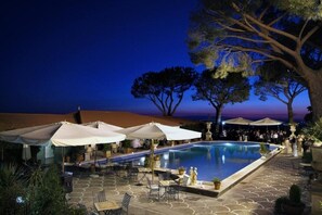 A poolside area with umbrellas, seating, and a view of the beach at dusk. - Grand Hotel Helio Cabala (Marino)