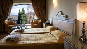 A hotel room with two beds, a balcony with a view of trees and a distant landscape, a table with tea set, and a lamp. - Grand Hotel Helio Cabala (Marino)