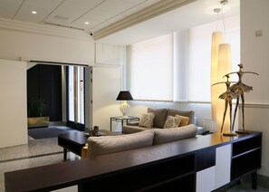 A modern living room with a sofa, a coffee table, a lamp, and a decorative sculpture. - Hostal Carlos III (Getafe)