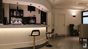 Un área de bar con una barra curva, dos taburetes y una máquina de café.