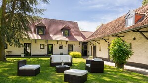 A courtyard with outdoor furniture, a building with a tiled roof, and a tree.