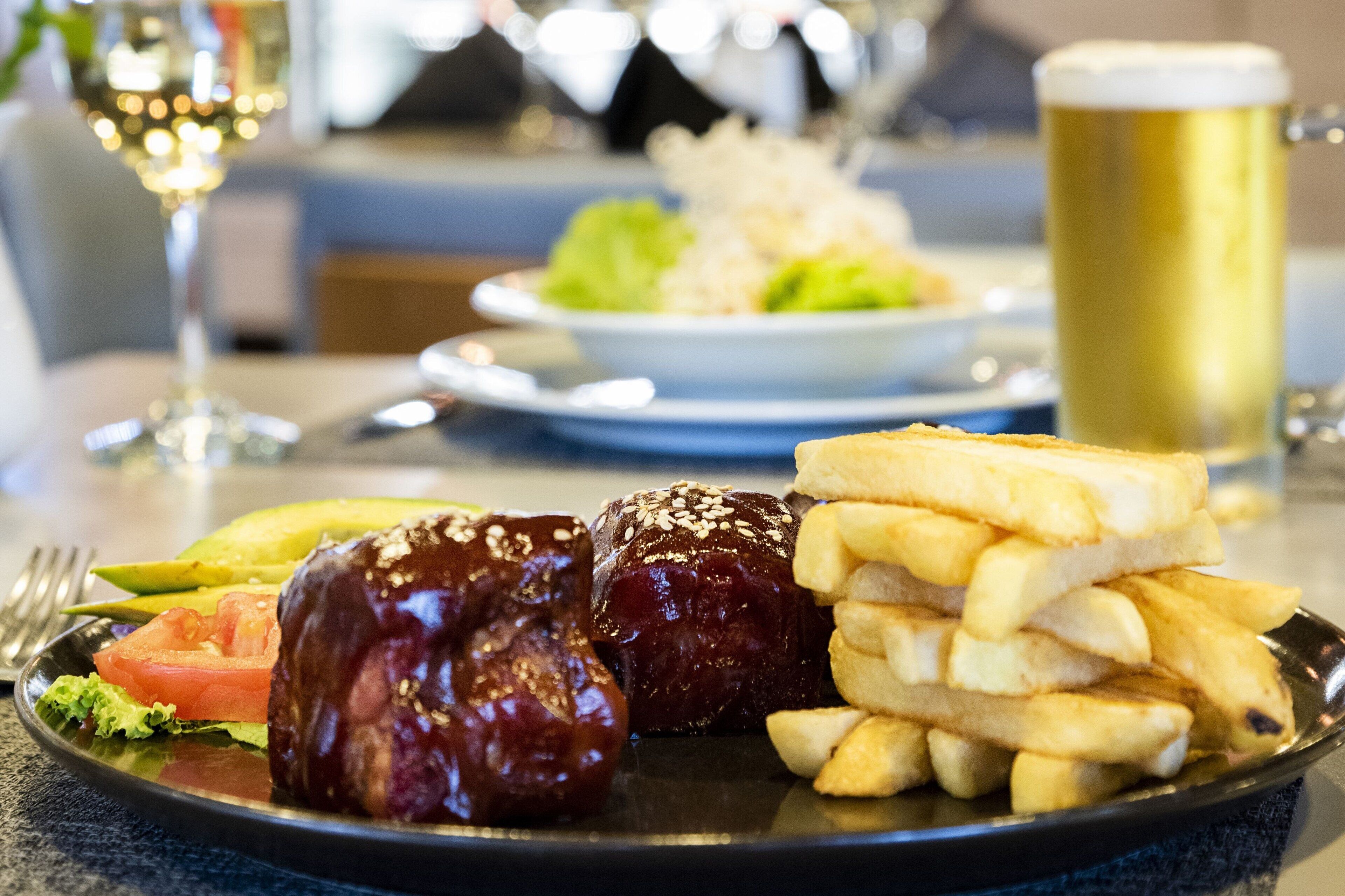 A plate with food including a glazed meat, fries, and a salad.
