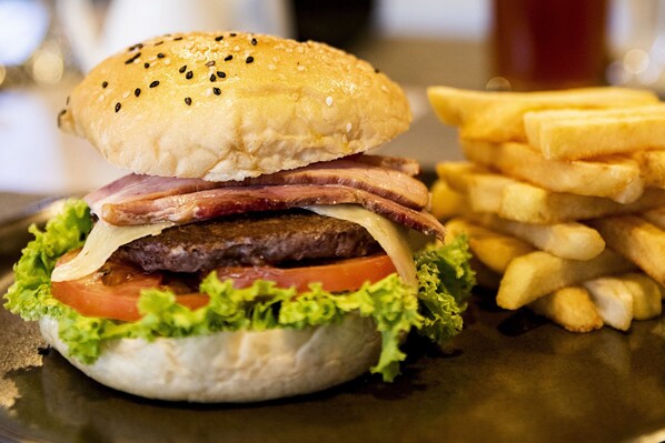Una hamburguesa con lechuga, tomate, queso y tocino, acompañada de papas fritas.