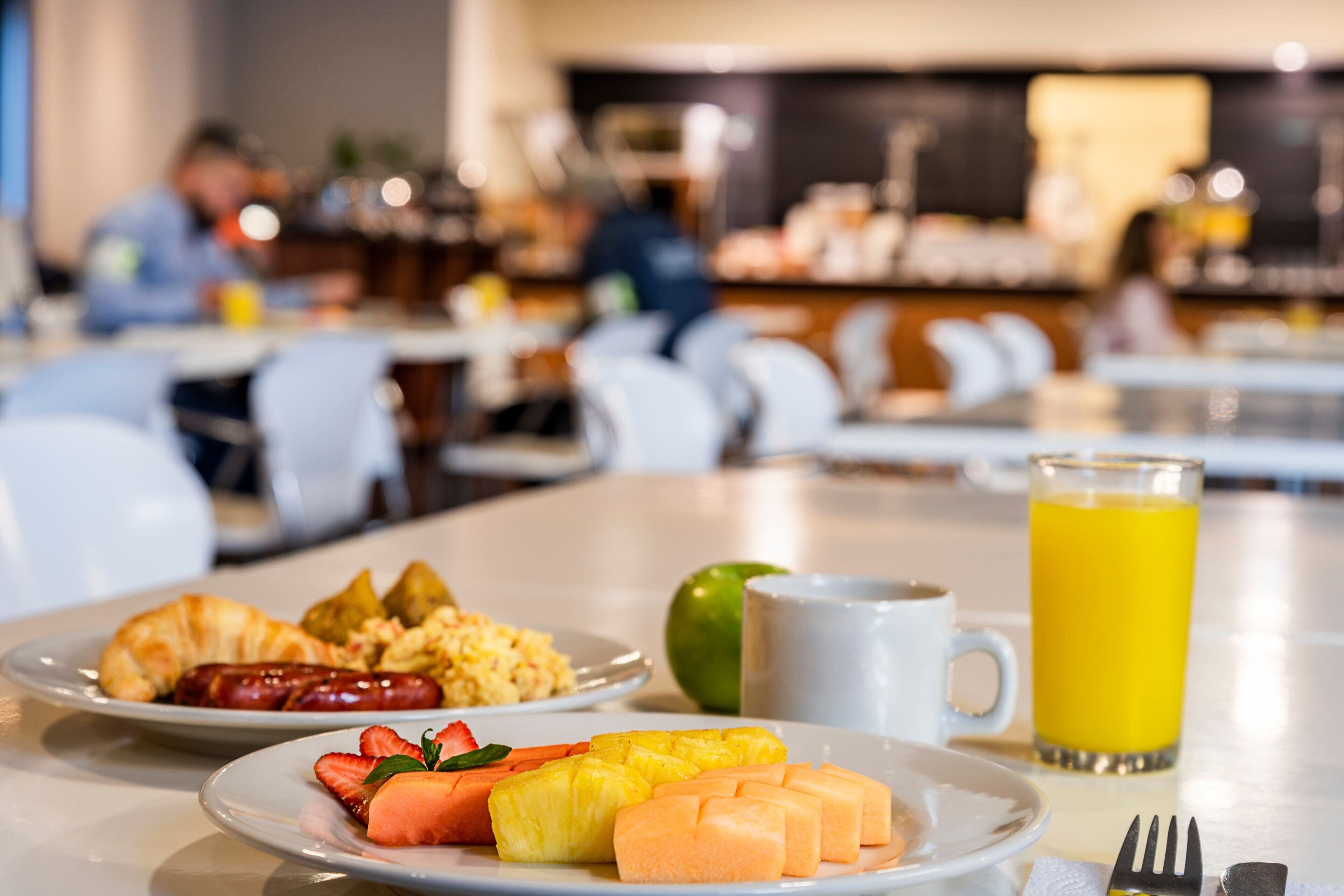 A breakfast setting with plates of food, a glass of orange juice, and a coffee cup.