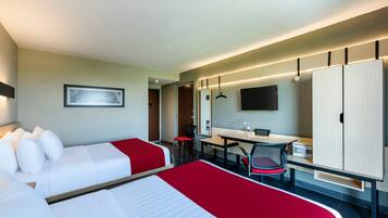A hotel room with two beds, a desk, a chair, a TV, and a wardrobe.