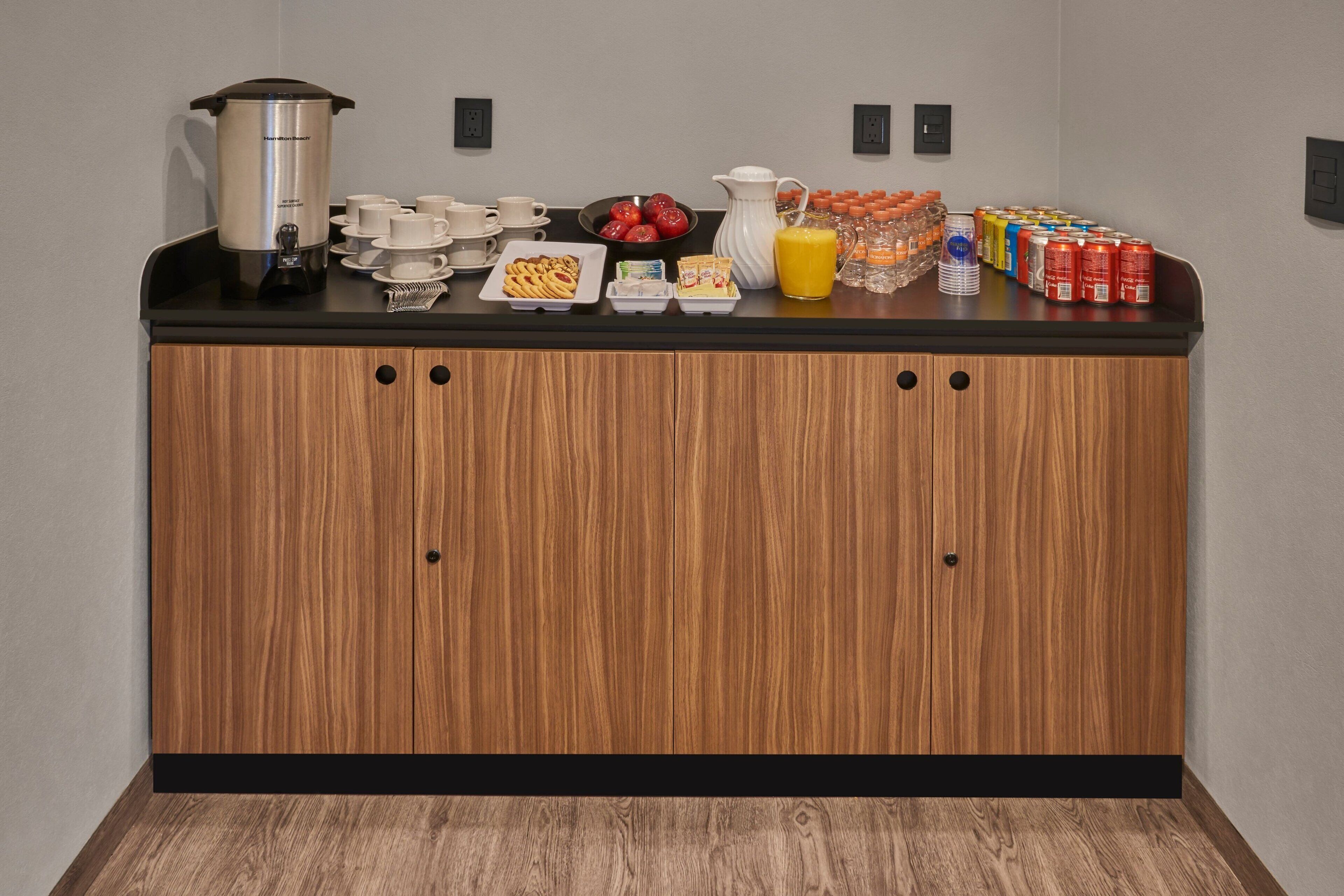 Morgenmadsbuffet med kaffemaskine, frugt, juice og forskellige drikkevarer.