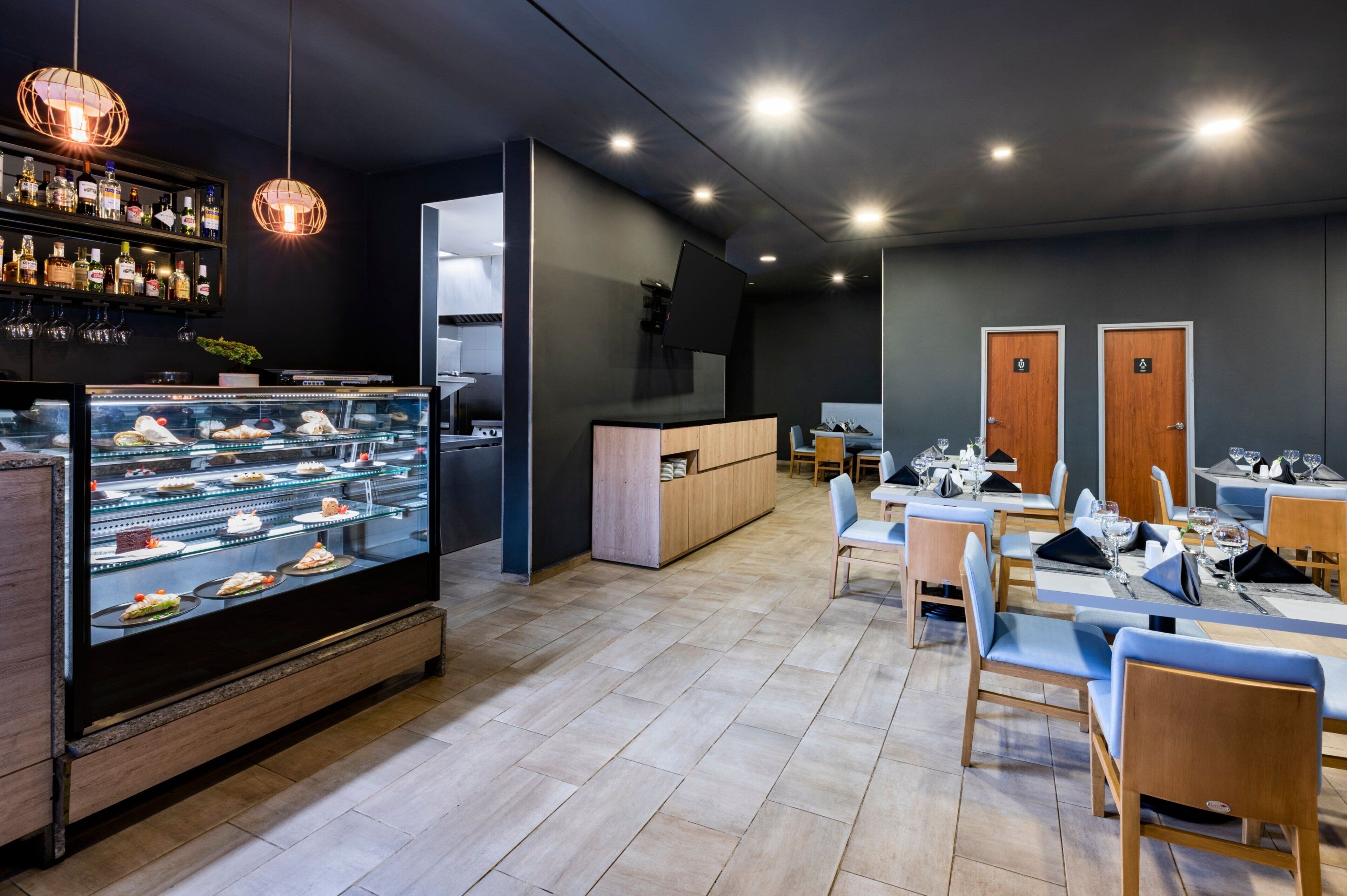 A modern restaurant with a dessert display, seating area, and bar.