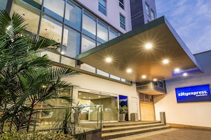 Entrada moderna de hotel con puertas de vidrio, un área exterior cubierta y el letrero de CityExpress.