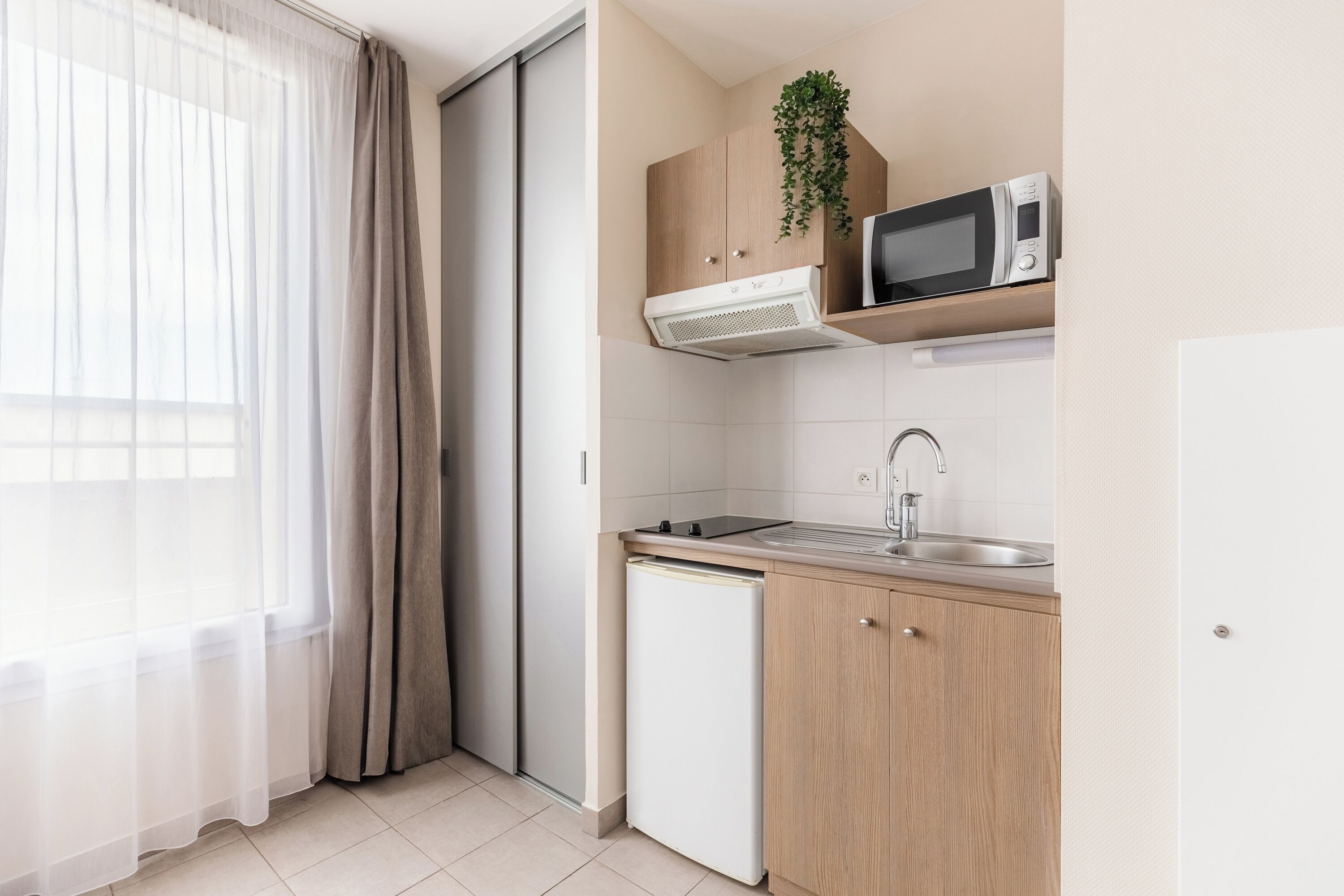 A compact kitchen with a microwave, sink, and a small refrigerator.