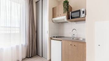 A compact kitchen with a microwave, sink, and a small refrigerator.