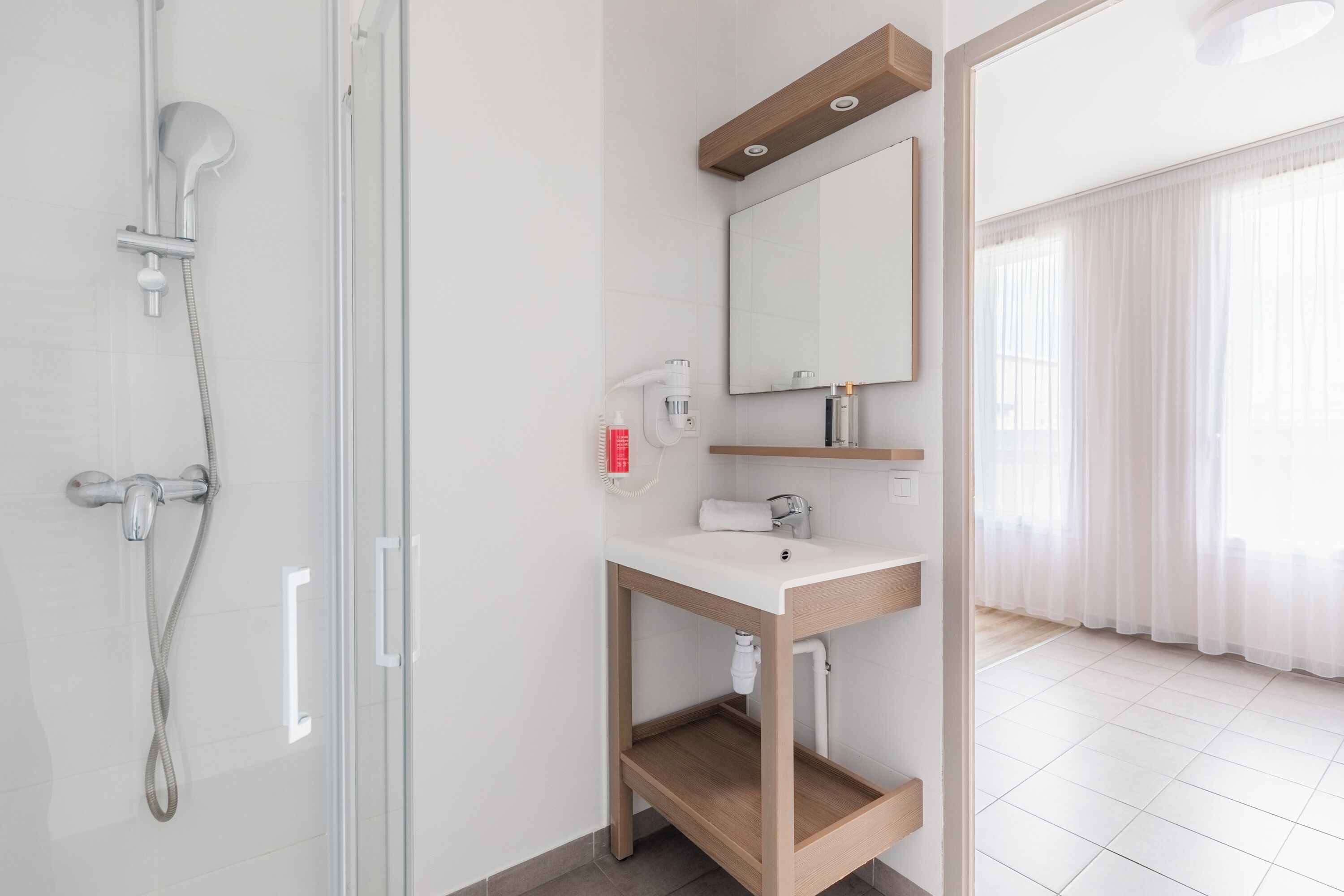 A modern bathroom with a shower, a sink, and a mirror.