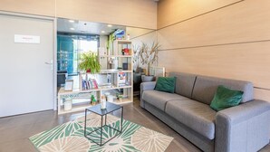 Ein moderner Empfangsbereich mit grauem Sofa, Couchtisch und Bücherregal.