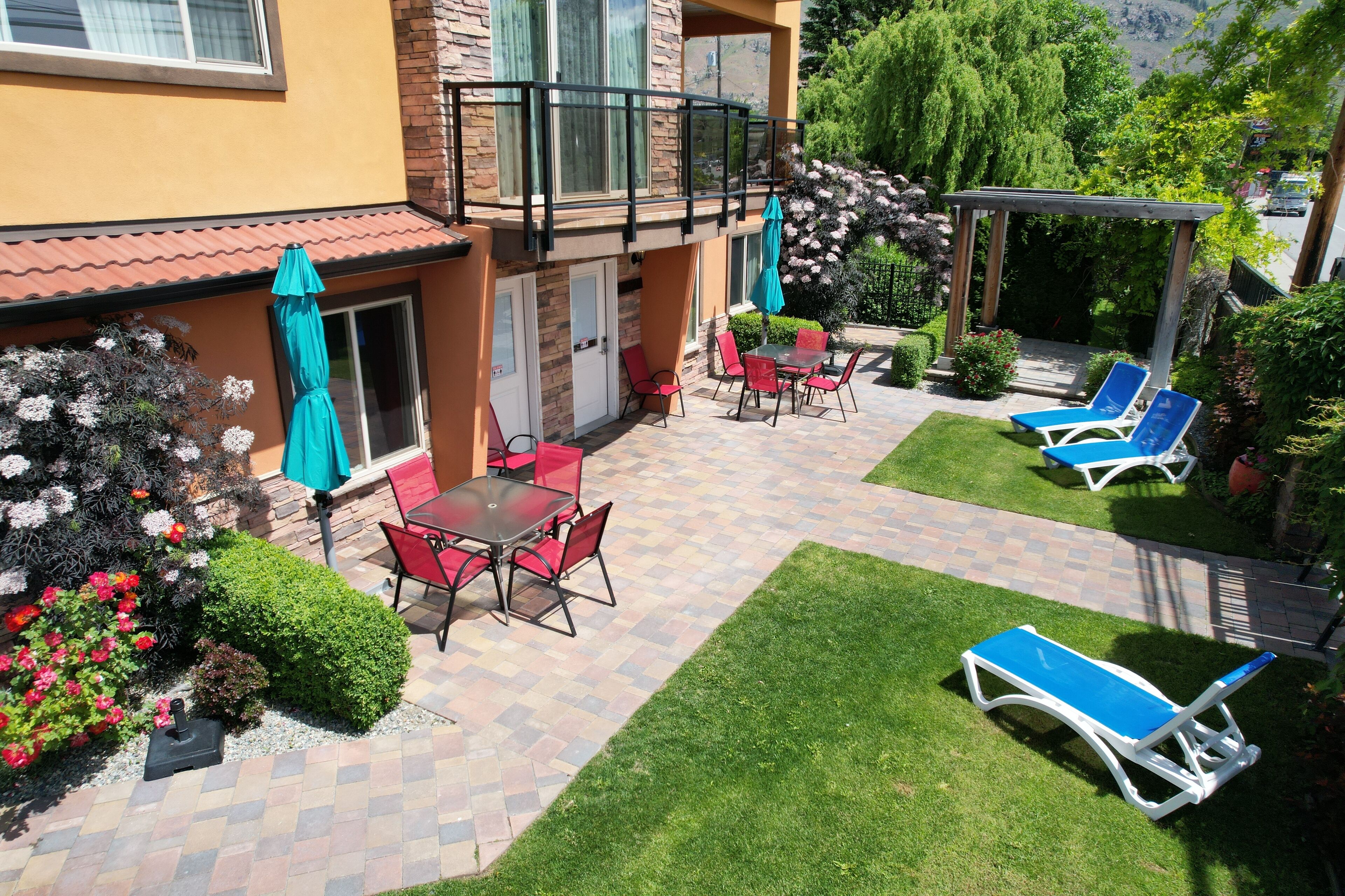 Une terrasse avec une table et des chaises, un fauteuil de jardin bleu et une pergola.
