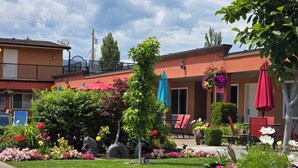 A hotel courtyard with a well-maintained lawn, outdoor seating area with chairs and tables, and a variety of colorful flowers and plants. - Sahara Courtyard Inn (Osoyoos)