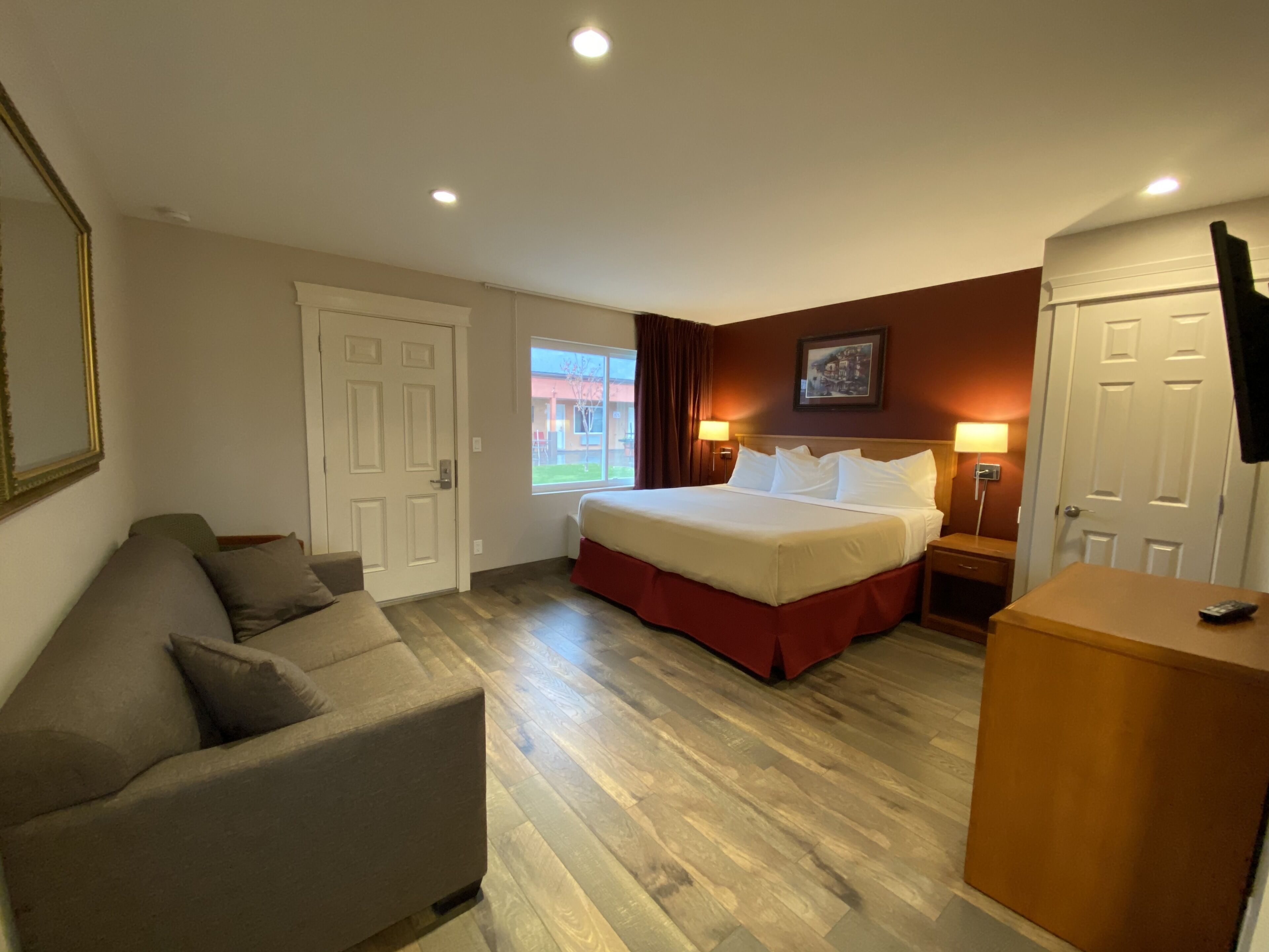 Una camera d'albergo con un letto, un divano, una scrivania e una televisione.