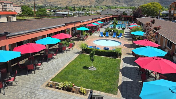 A courtyard with a swimming pool, outdoor seating, and a view of mountains. - Sahara Courtyard Inn (Osoyoos)