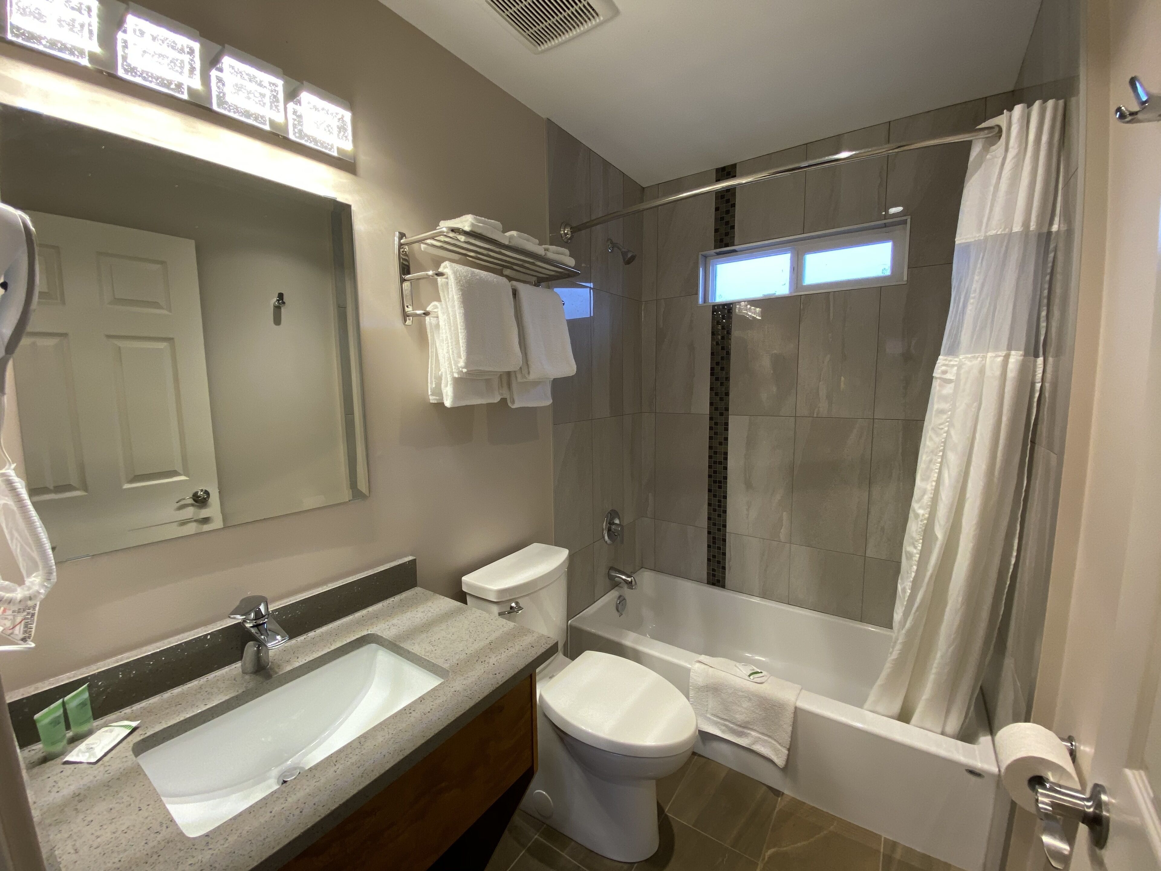Un bagno moderno con un grande specchio, un lavabo, un WC e una vasca da bagno.