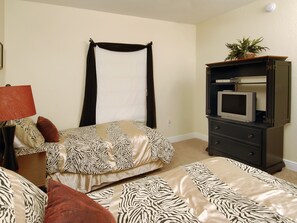 A bedroom with a bed, a dresser, a television, and a lamp.