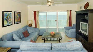 A living room with a sofa, a coffee table, a television, and a balcony with a view. - Crystal Shores by Wyndham Vacation Rentals (Gulf Shores)