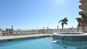 A clear blue pool with a hot tub, surrounded by a white fence and palm trees. - Crystal Shores by Wyndham Vacation Rentals (Gulf Shores)