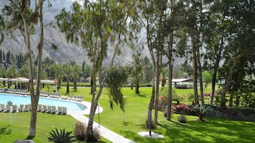 Una piscina al aire libre, sombrillas, sillones reclinables de piscina