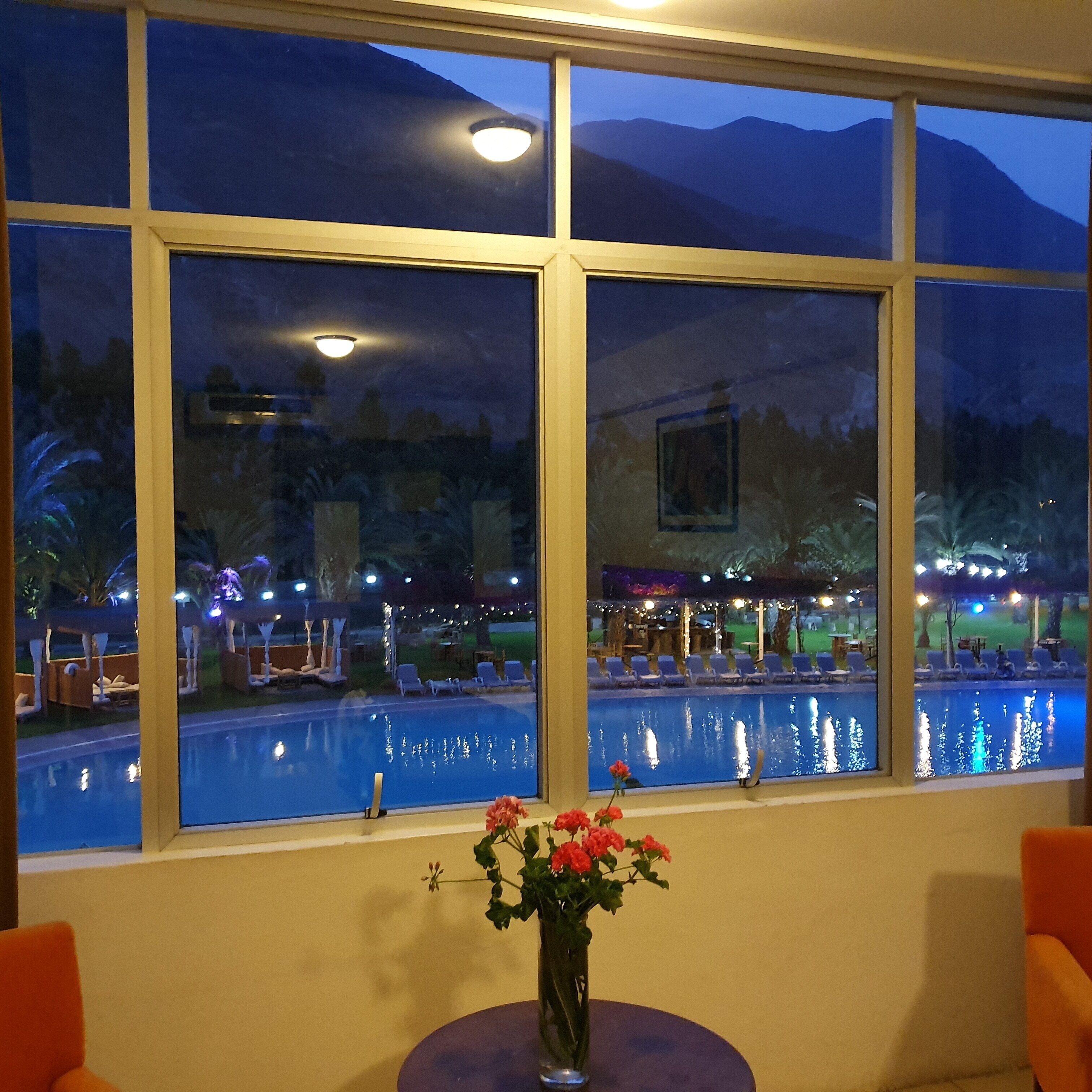 A view of a pool area with a mountain backdrop through large windows.