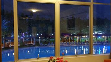 A view of a pool area with a mountain backdrop through large windows.