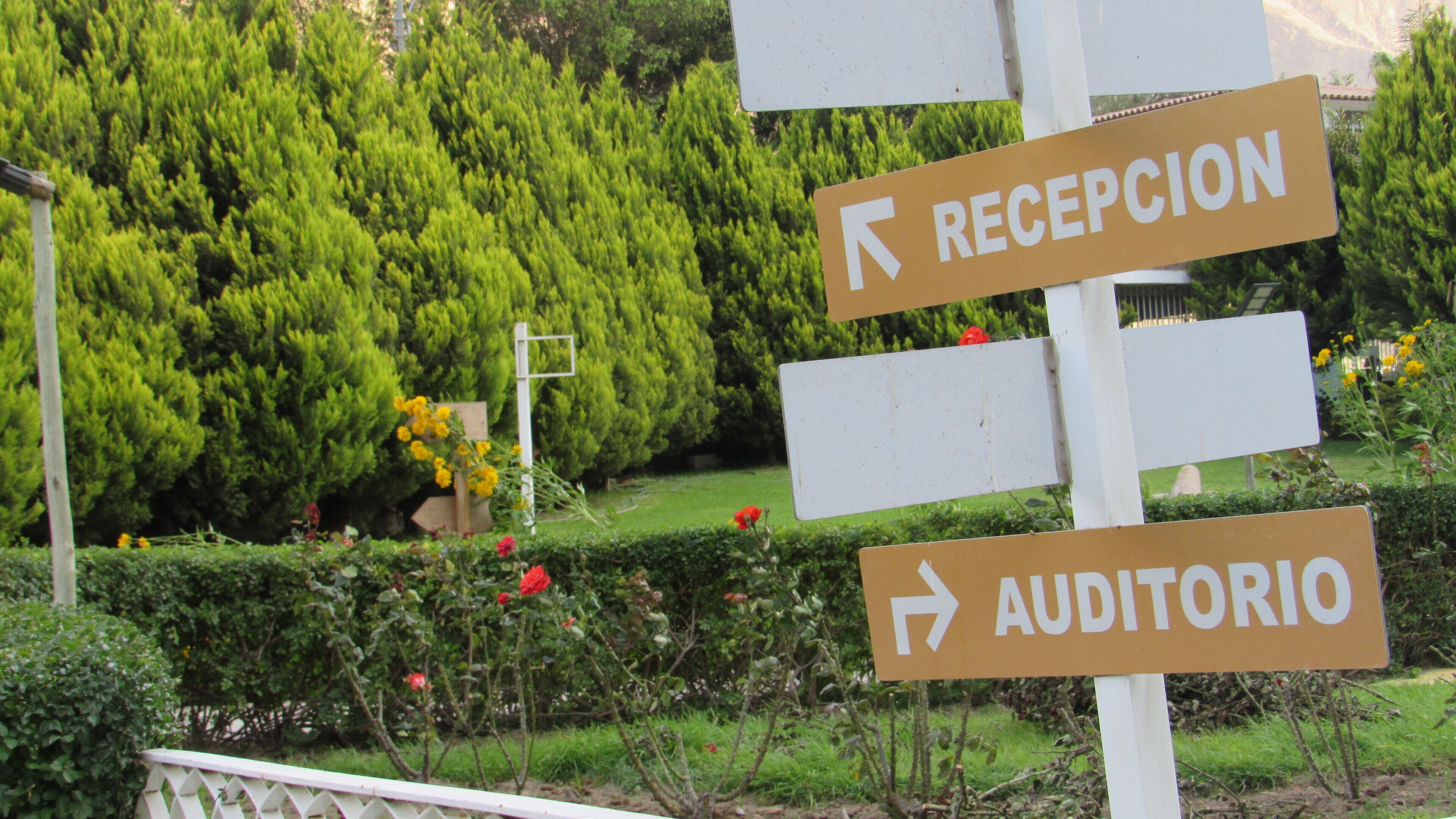 A directional sign with arrows pointing to 'RECEPCION' and 'AUDITORIO'.