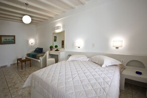 Quarto com uma cama grande, uma mesa de escritório e uma cadeira. Há luminárias na parede e uma luminária no teto.
