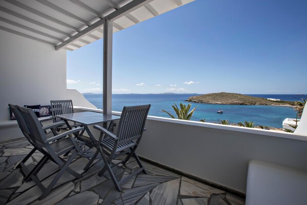 A balcony with a table and chairs overlooking a coastal view.