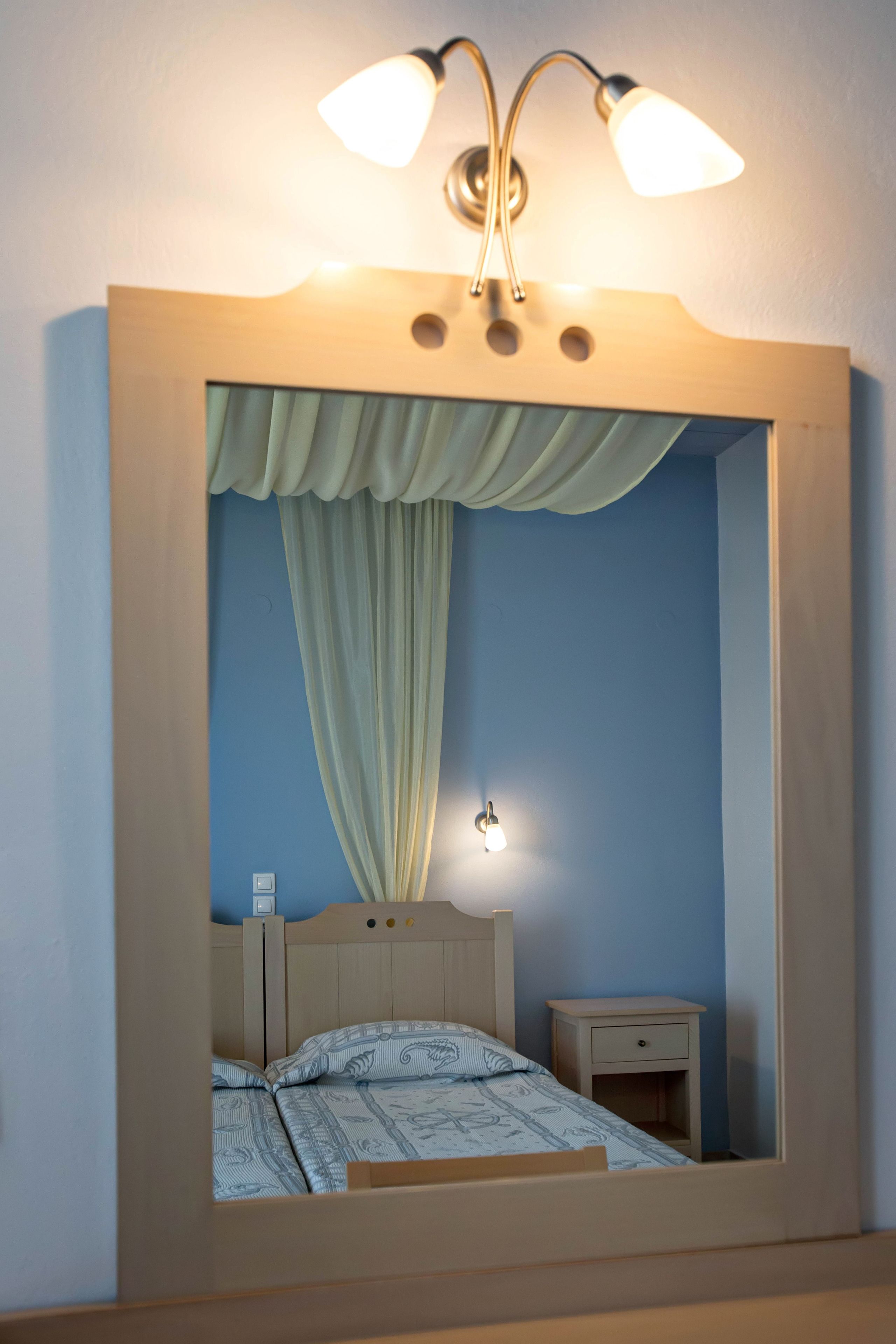 Une chambre à coucher avec un lit, une table de chevet et un luminaire fixé au mur.