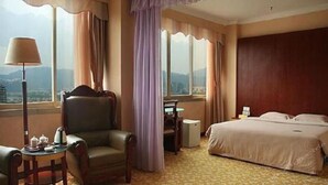 A hotel room with a bed, a chair, a desk, and a lamp. - Haoting Commercial Hotel - Zhuhai (Zhuhai)