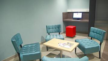 A seating area with four blue chairs, a wooden table, and a red cube.