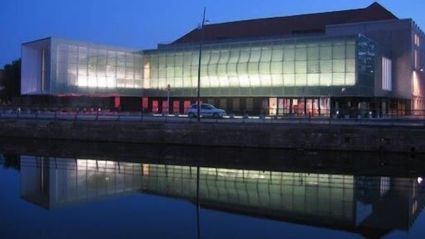 Een modern gebouw met een glazen gevel die weerspiegelt in het water.