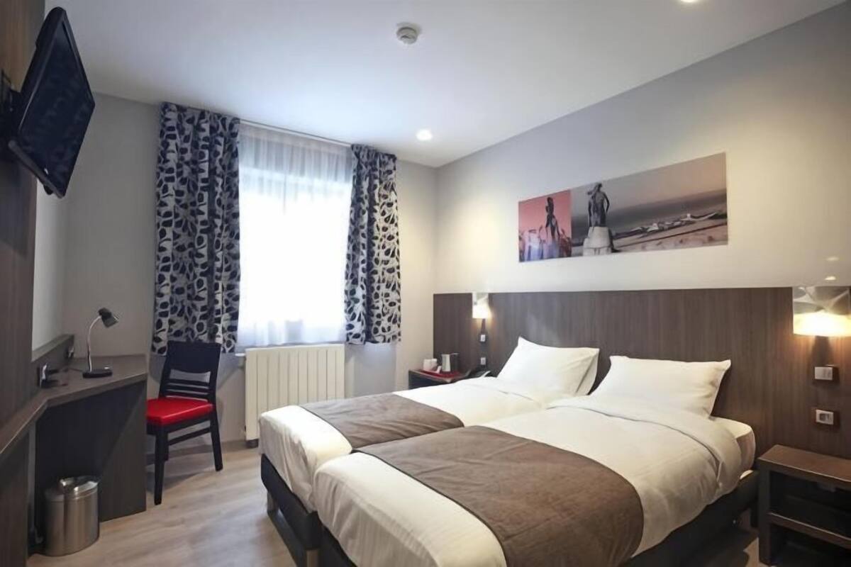 Une chambre dâhĂŽtel avec un lit, un bureau, une chaise et un tableau au mur.